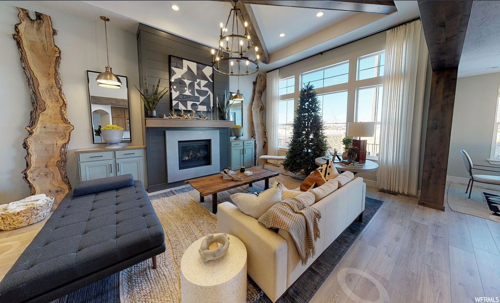 Living room with hardwood flooring, a fireplace, natural light, and a notable chandelier