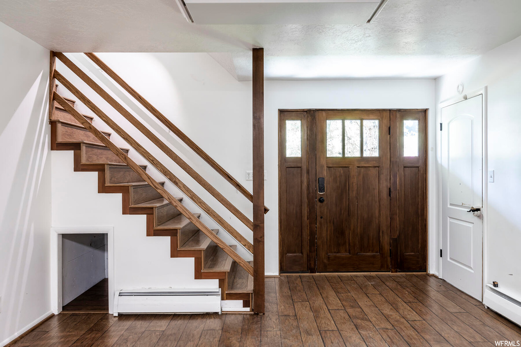 Wood floored foyer entrance with a baseboard radiator