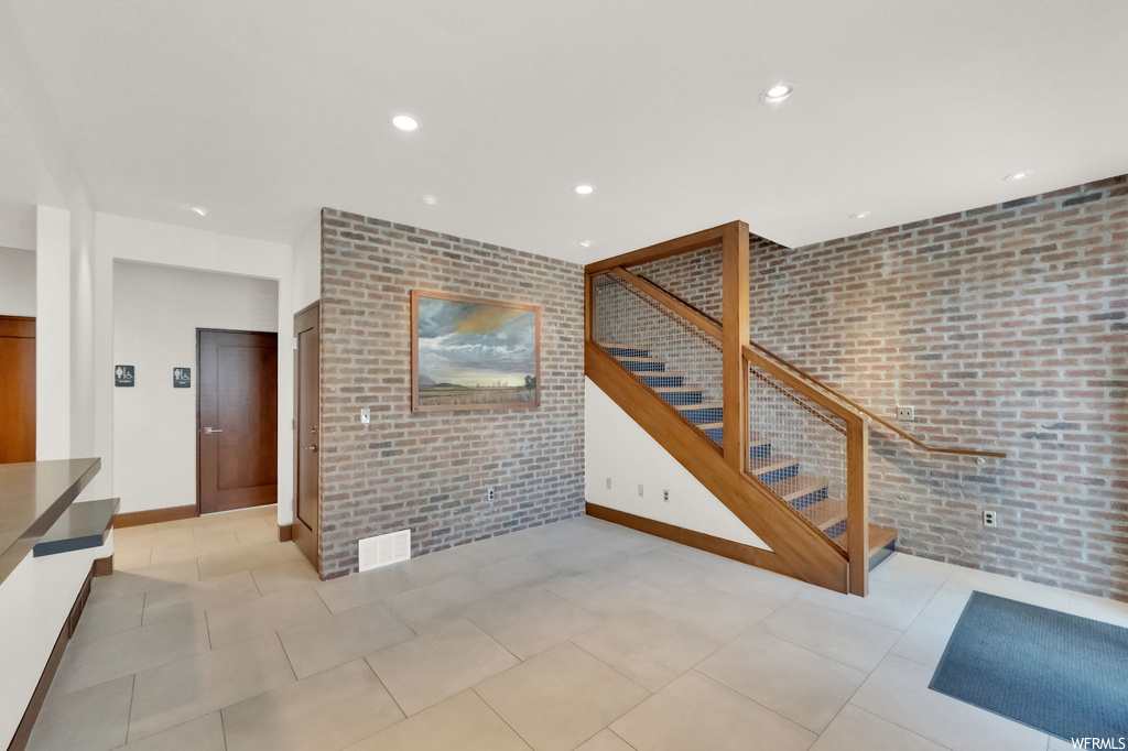 Tiled living room featuring brick wall