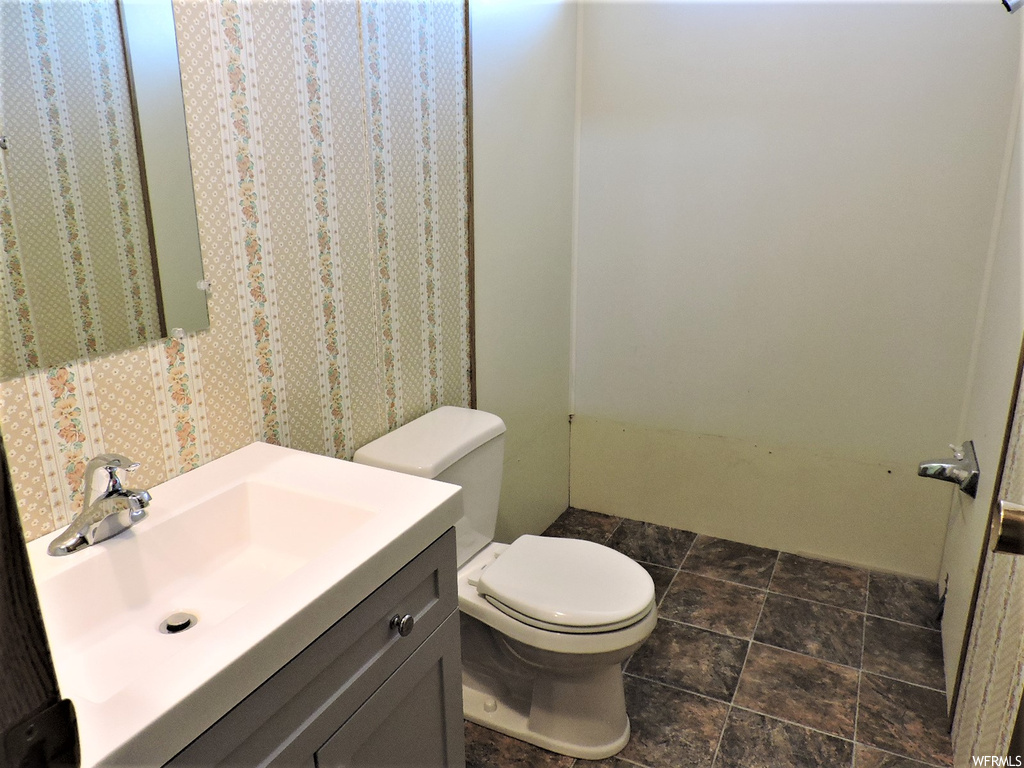 Bathroom featuring tile flooring, toilet, shower curtain, mirror, and vanity