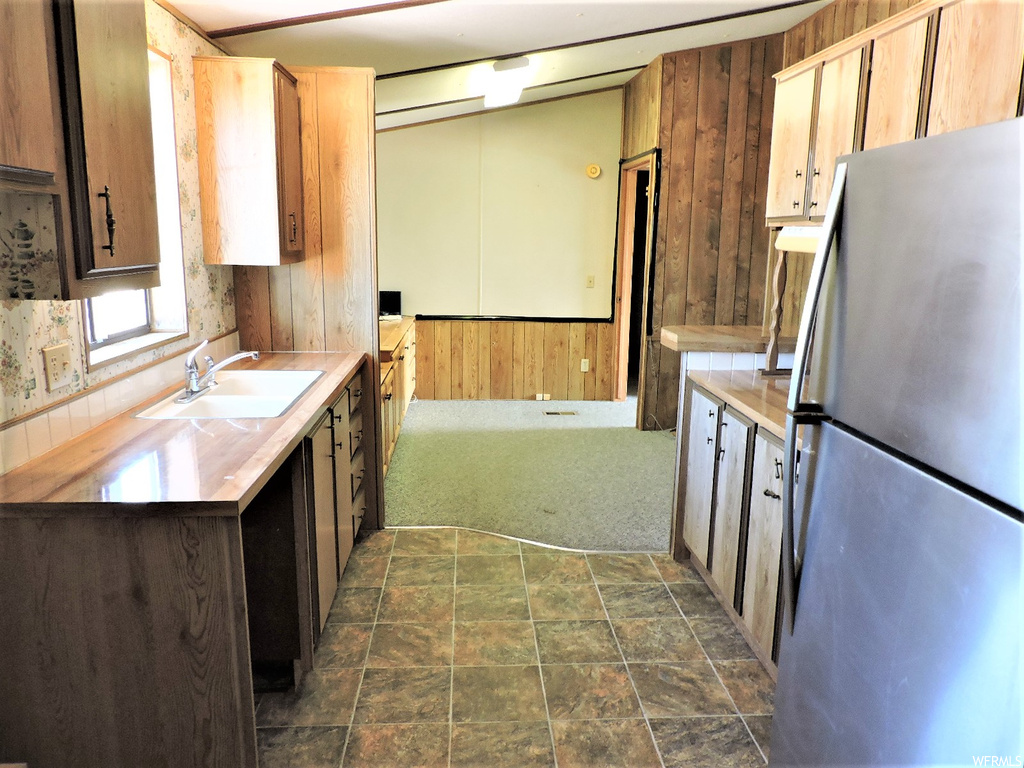 Kitchen featuring refrigerator, light countertops, and dark tile flooring