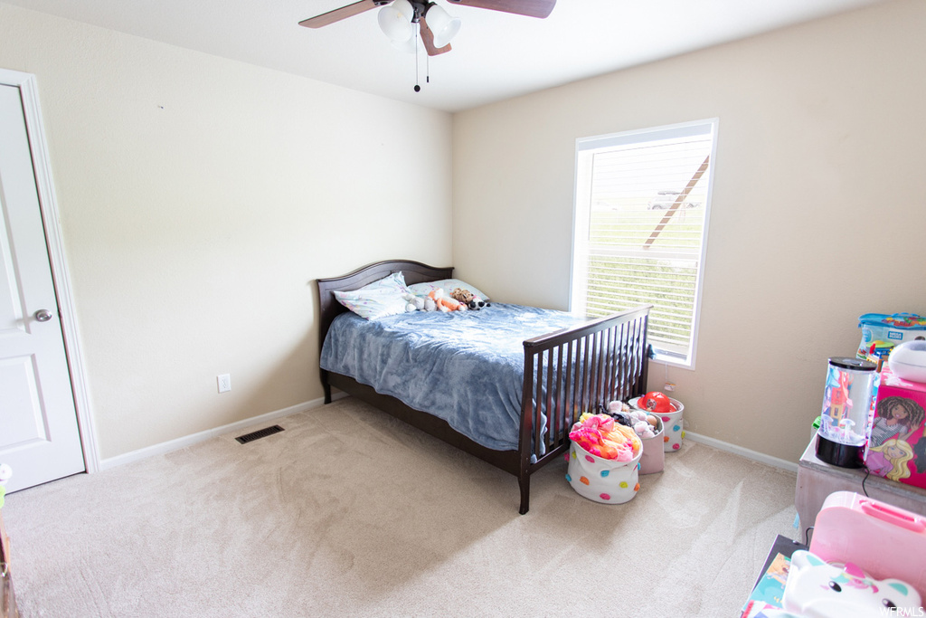 Bedroom featuring a ceiling fan, carpet, and natural light