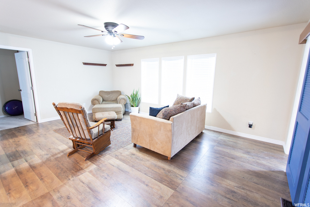 Living room featuring natural light, hardwood flooring, and a ceiling fan