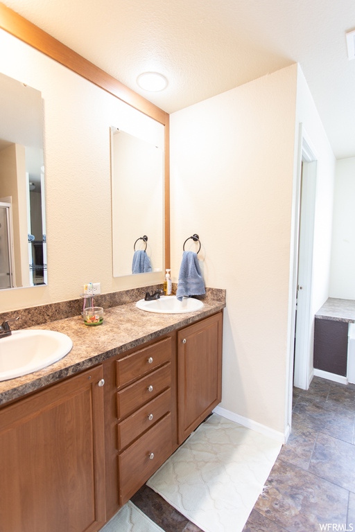 Bathroom featuring tile floors, mirror, and dual vanity