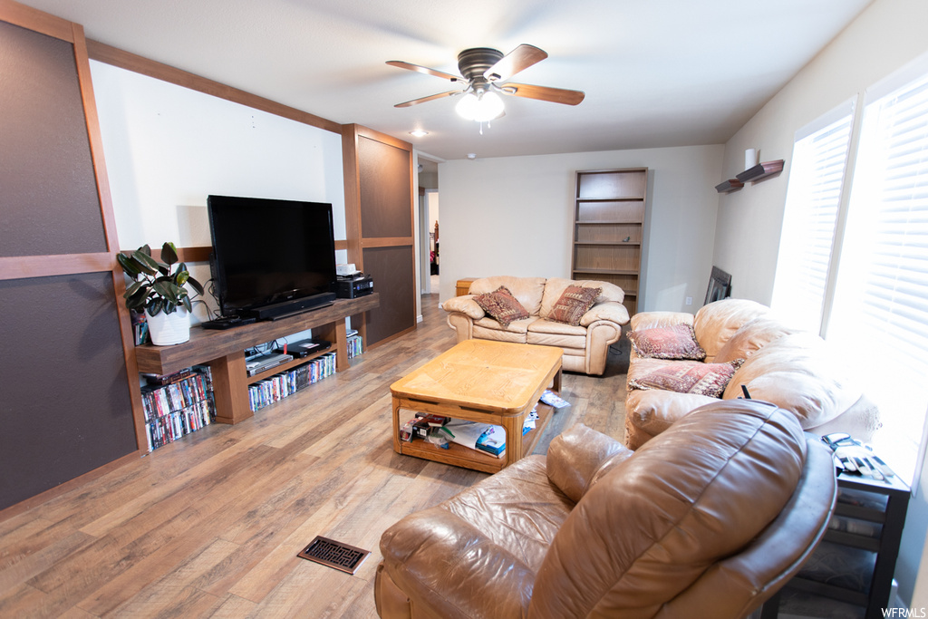 Hardwood floored living room featuring a ceiling fan and TV