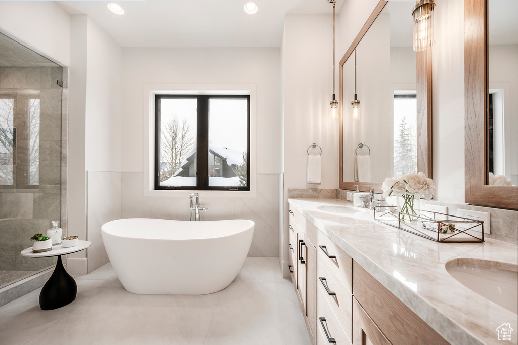 Bathroom featuring tile floors, a wealth of natural light, large vanity, and dual sinks