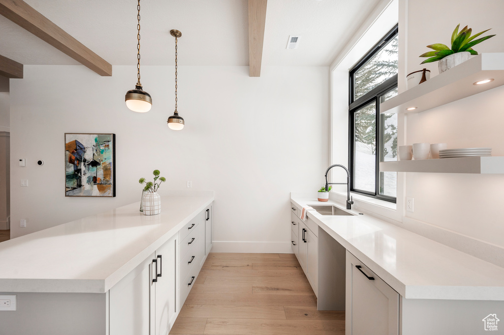 Kitchen with sink, decorative light fixtures, beam ceiling, and a healthy amount of sunlight