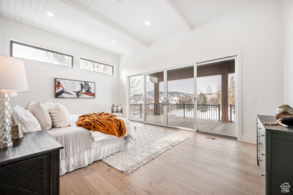 Bedroom featuring beamed ceiling, access to exterior, and light hardwood / wood-style flooring