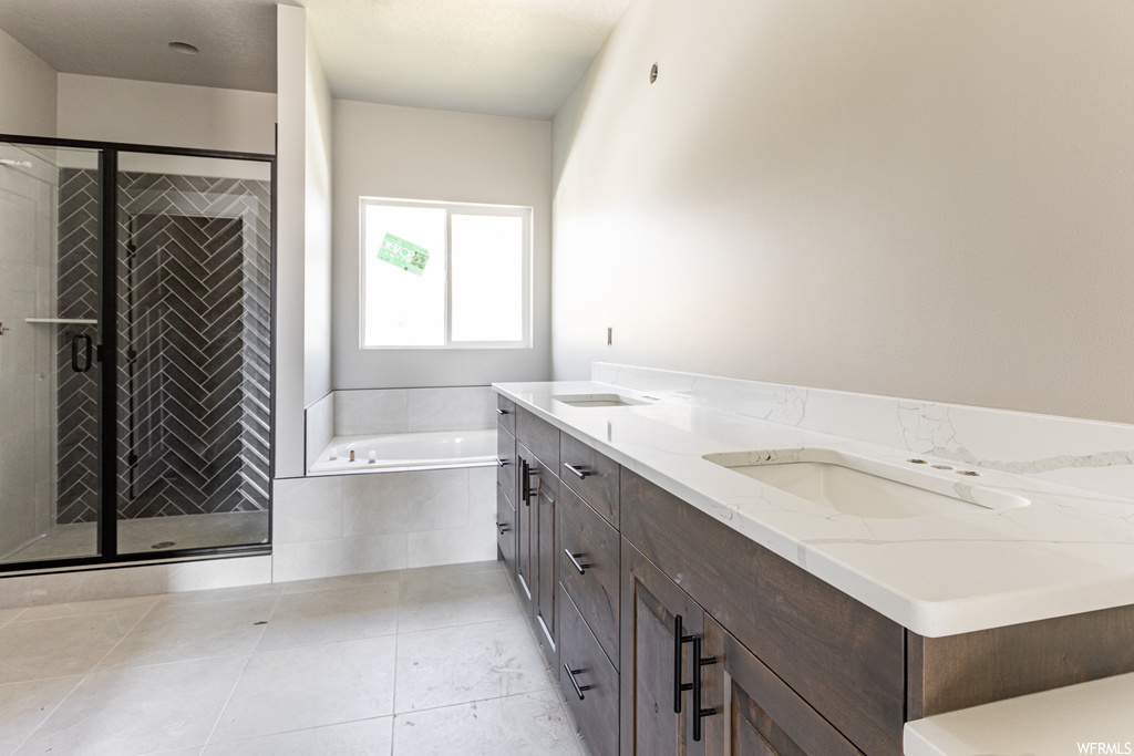 Bathroom featuring dual vanity, tile floors, and plus walk in shower