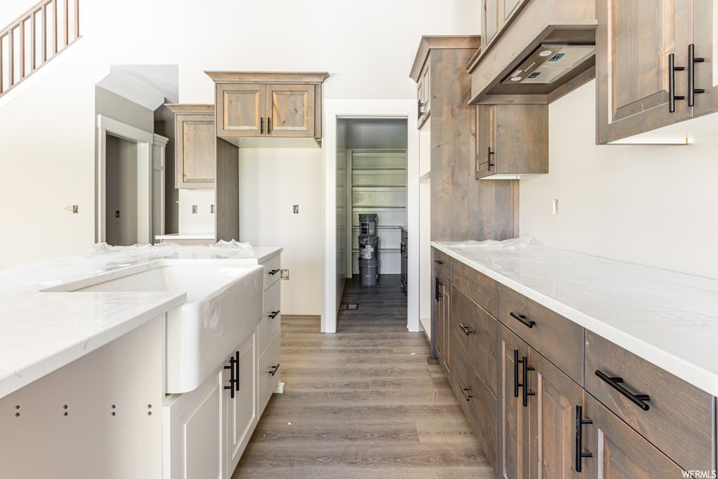 Kitchen featuring light wood-type flooring, custom range hood, and light stone countertops