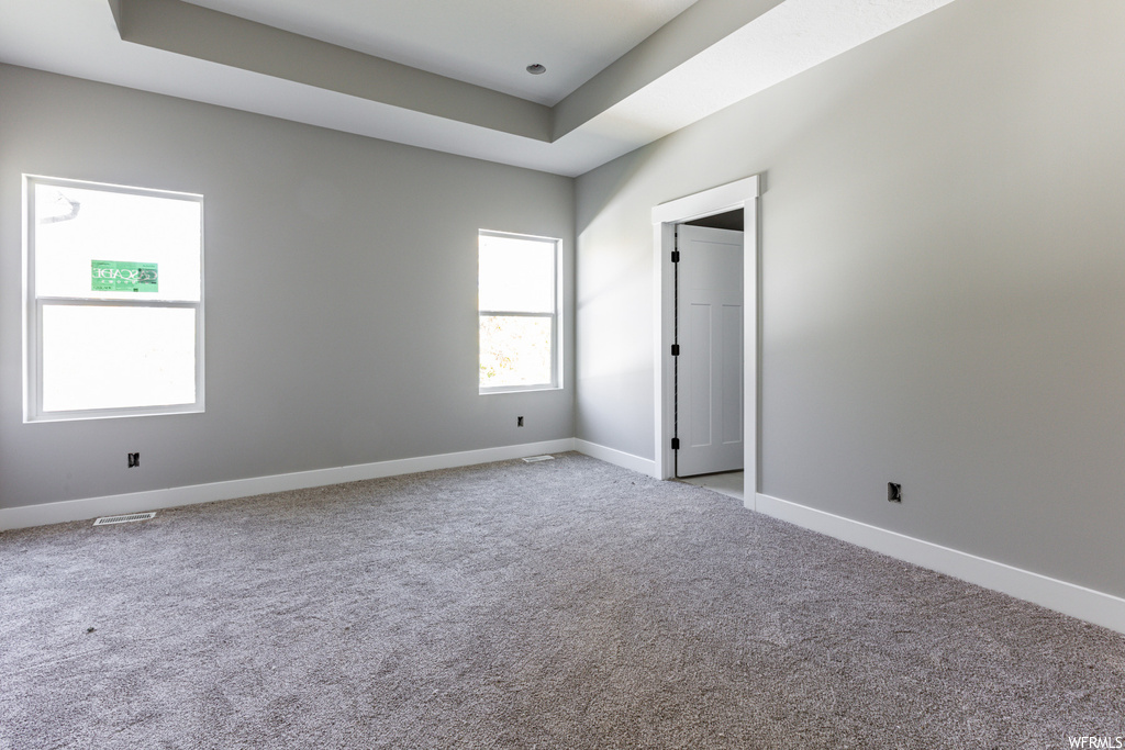 Spare room featuring a tray ceiling and light carpet