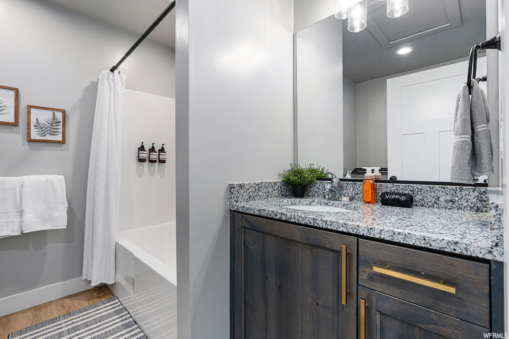 Bathroom with hardwood floors, shower curtain, mirror, bath / shower combination, and vanity