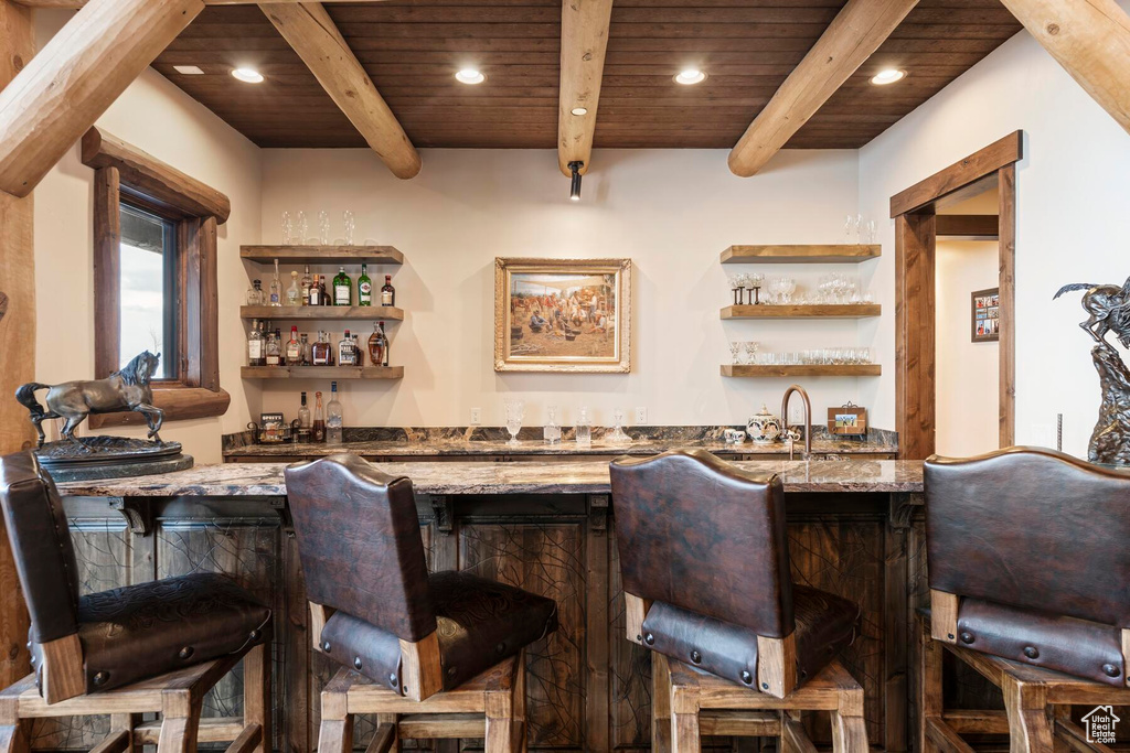 Bar with beam ceiling, dark stone counters, wooden ceiling, and sink