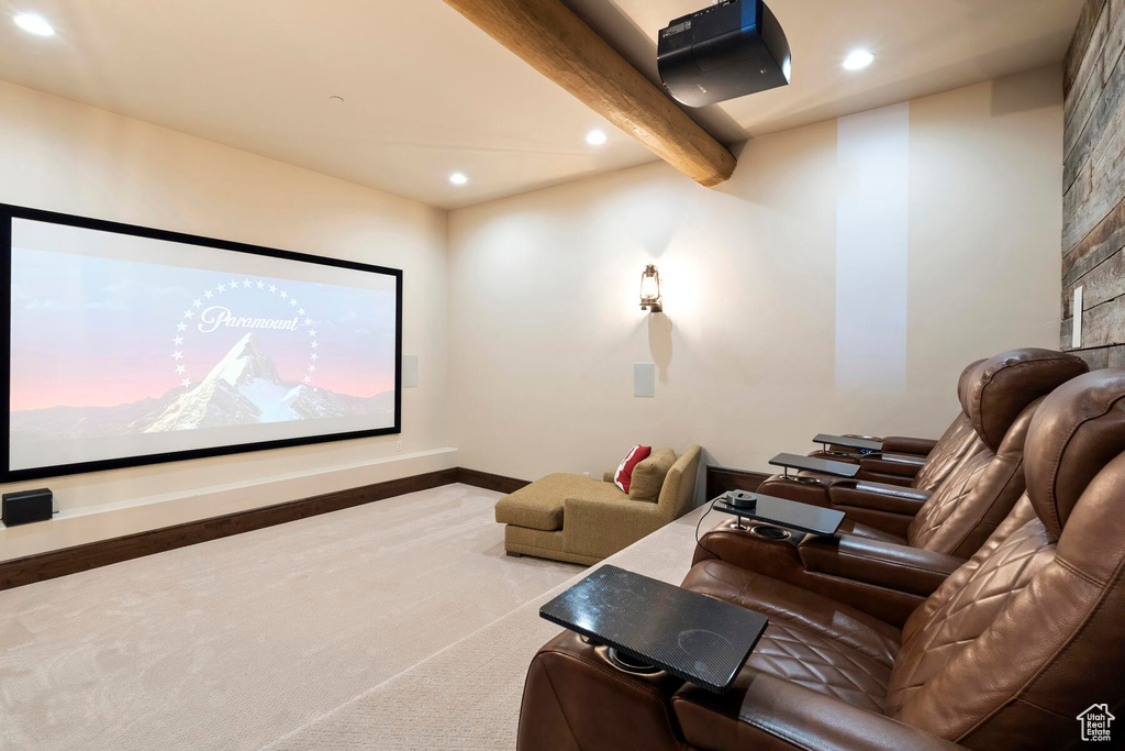Carpeted cinema room featuring beamed ceiling