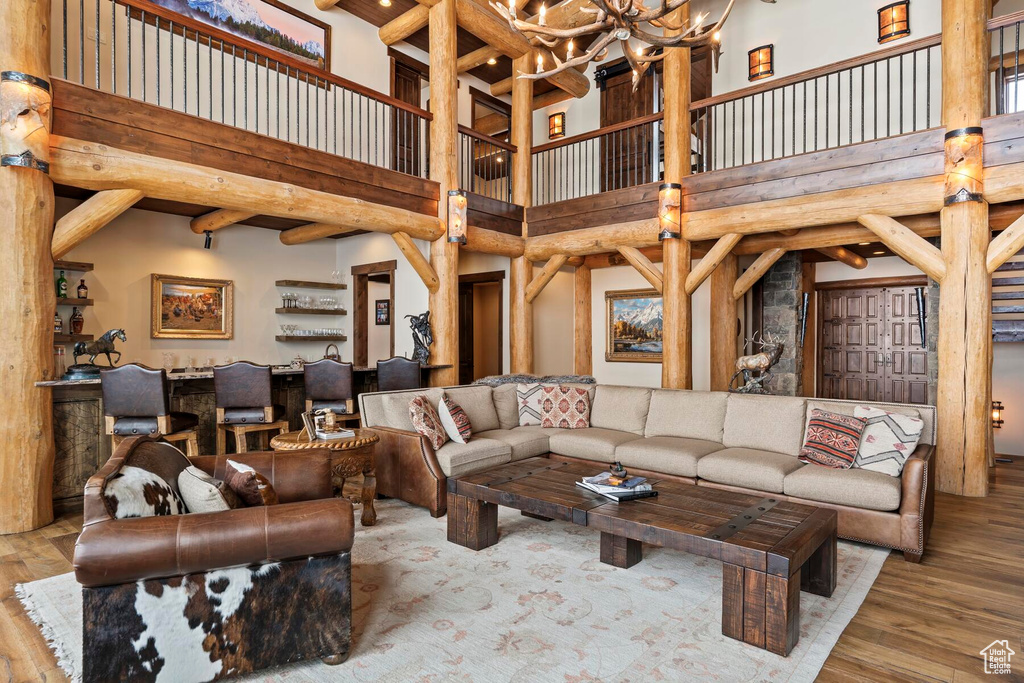 Living room featuring a towering ceiling, beam ceiling, a chandelier, and light hardwood / wood-style floors