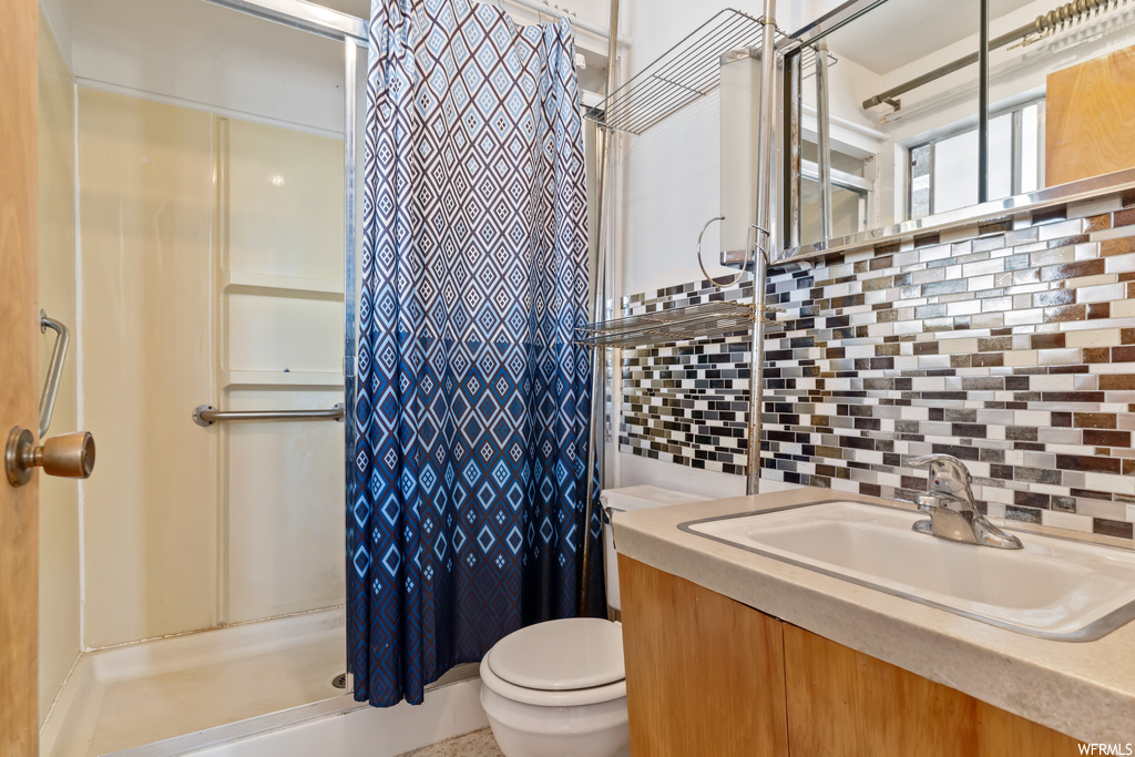 Bathroom featuring vanity with extensive cabinet space, a shower with curtain, mirror, and backsplash