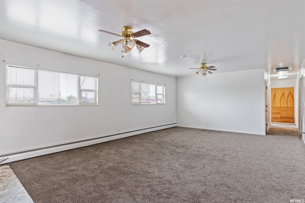 Empty room with light carpet, baseboard heating, and ceiling fan
