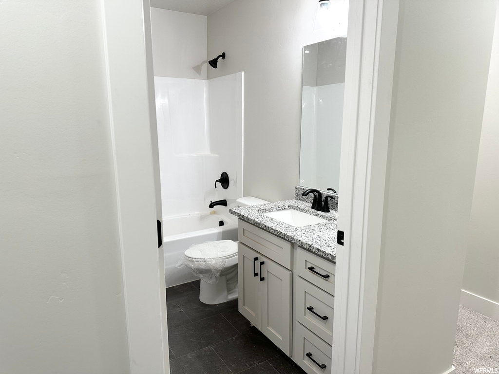 Full bathroom featuring toilet, tile floors,  shower combination, and vanity