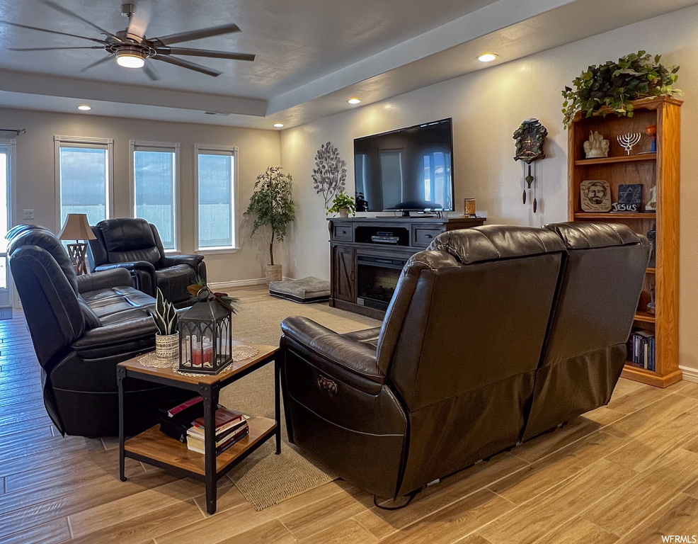 Living room featuring a ceiling fan, hardwood floors, natural light, and TV