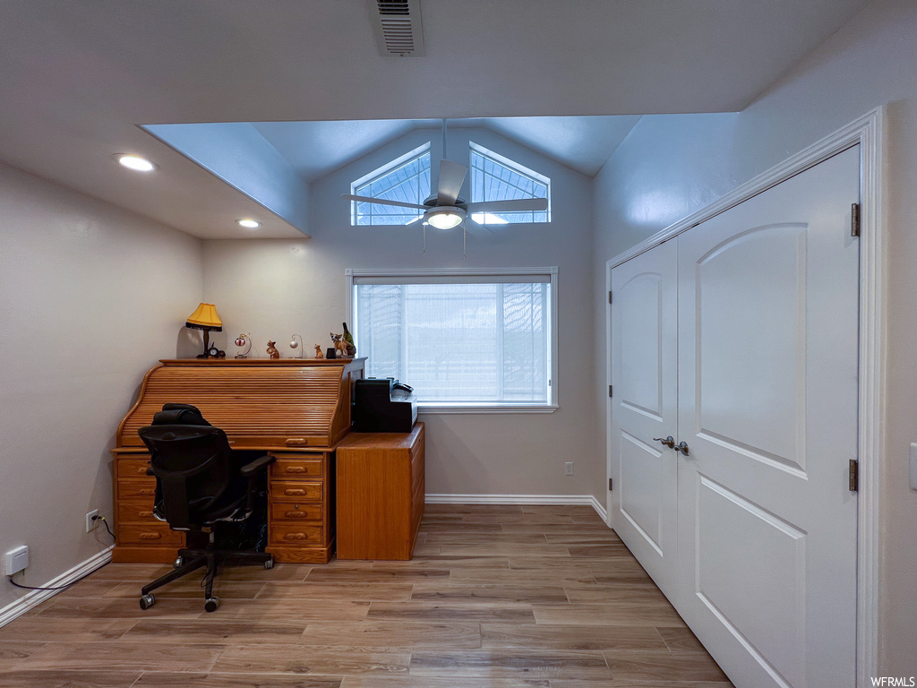 Home office with wood-type flooring, a ceiling fan, and natural light