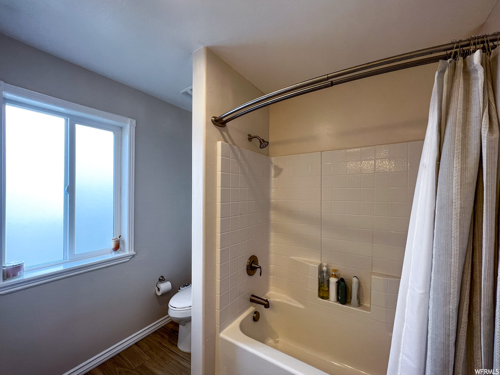 Bathroom featuring shower / washtub combination, toilet, and shower curtain
