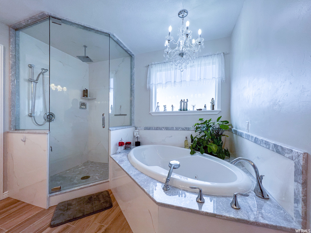 Bathroom featuring natural light, hardwood flooring, and separate shower and tub