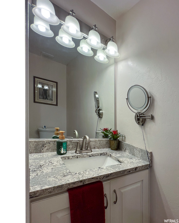 Half bath with vanity, mirror, and toilet