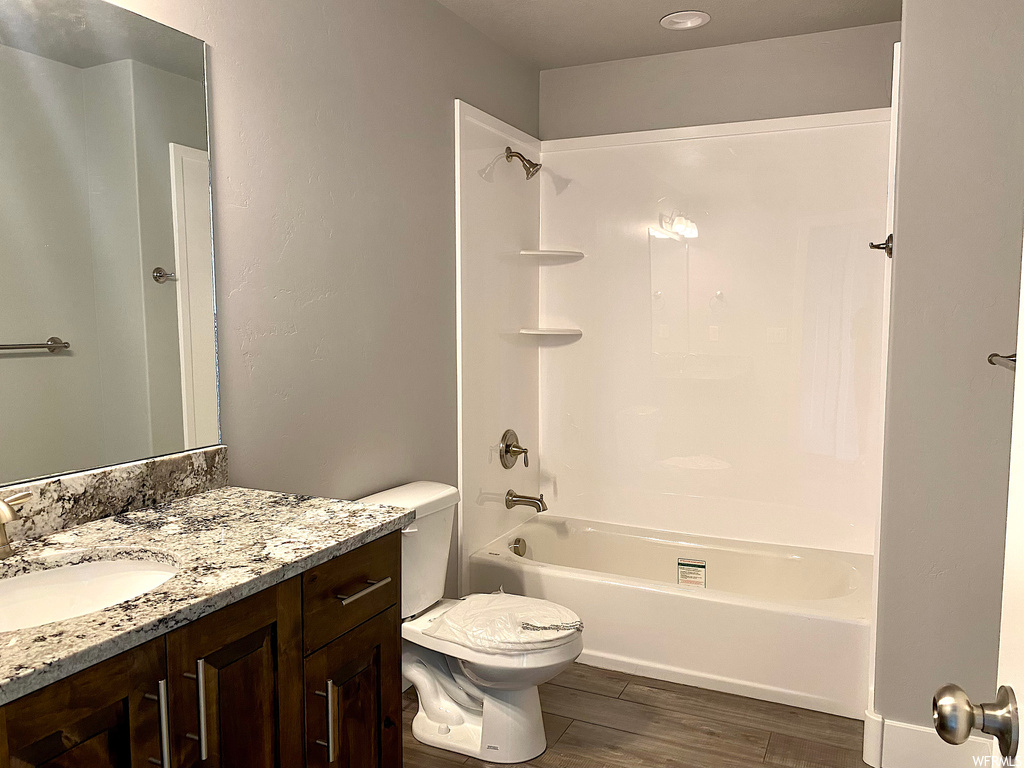 Full bathroom with bathtub / shower combination, mirror, large vanity, and toilet