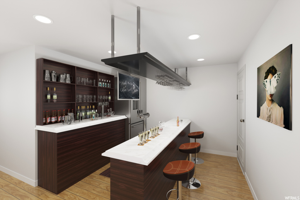 Bar featuring light countertops, dark brown cabinetry, and light parquet floors