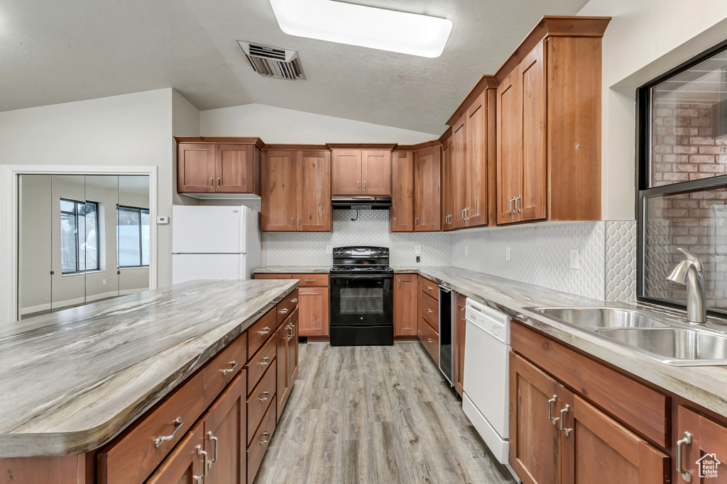 Kitchen featuring white appliances, sink, tasteful backsplash, light wood-type flooring, and vaulted ceiling