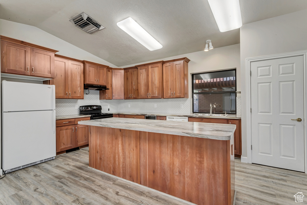 Kitchen with white fridge, light wood-type flooring, a center island, electric range, and tasteful backsplash