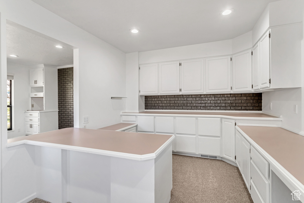 Kitchen with light carpet, white cabinets, and kitchen peninsula