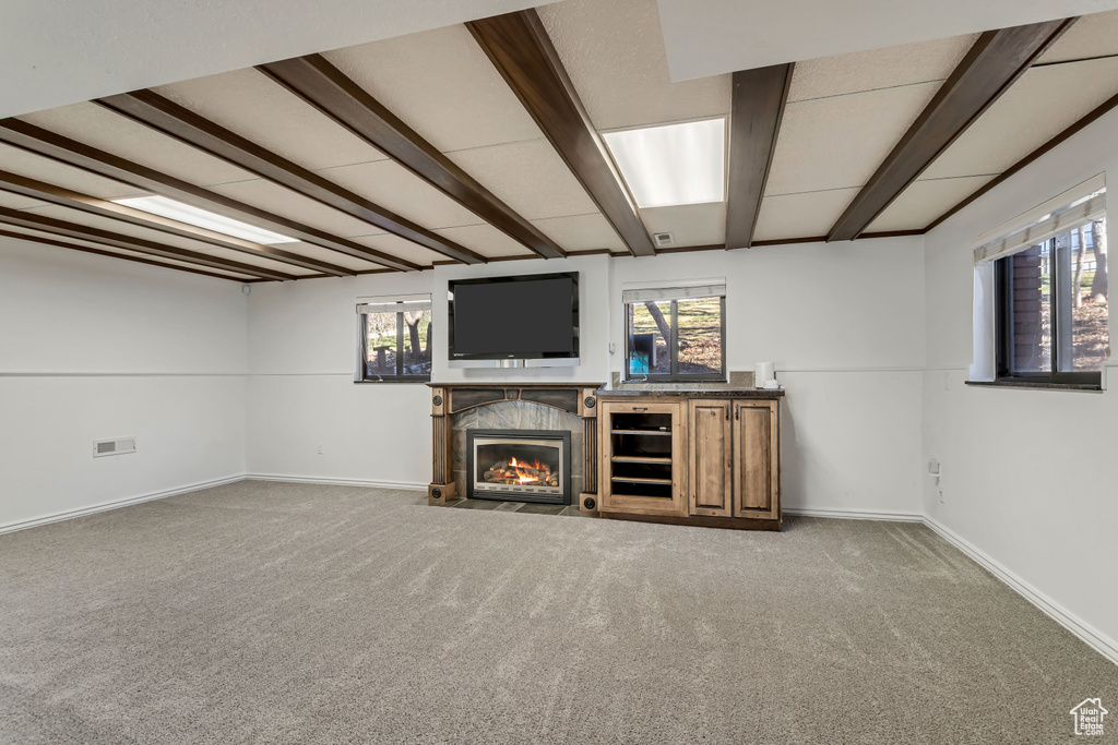 Basement featuring plenty of natural light, dark carpet, and a tile fireplace
