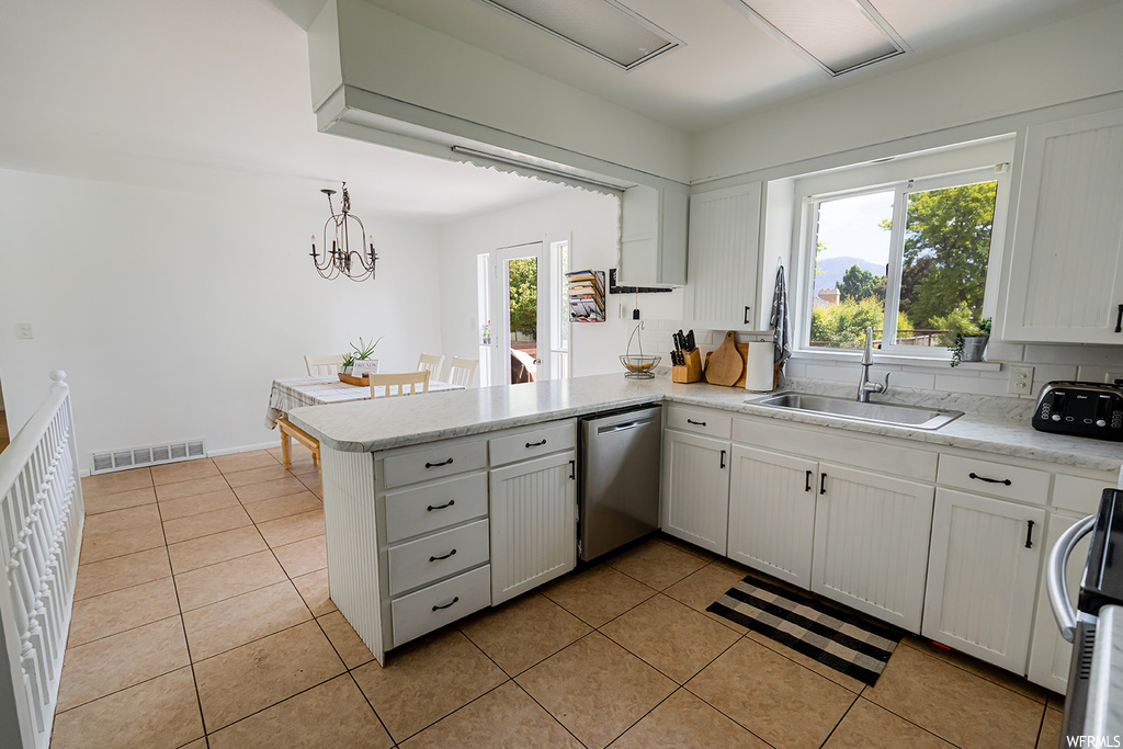 Kitchen with dishwasher, white cabinets, light tile floors, and light countertops