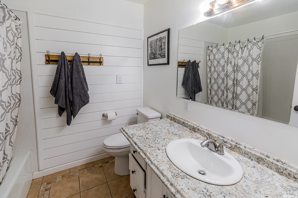 Full bathroom with tile floors, washtub / shower combination, mirror, toilet, shower curtain, and vanity