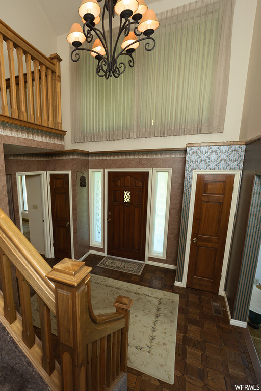 Entrance foyer featuring a notable chandelier, dark parquet floors, and lofted ceiling