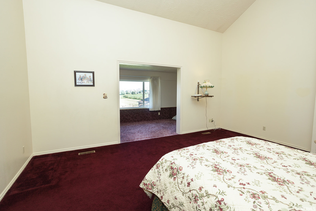 Bedroom featuring vaulted ceiling and dark carpet