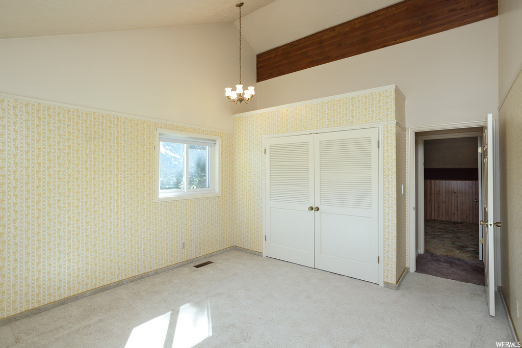 Bedroom featuring a chandelier, light carpet, vaulted ceiling, and a high ceiling