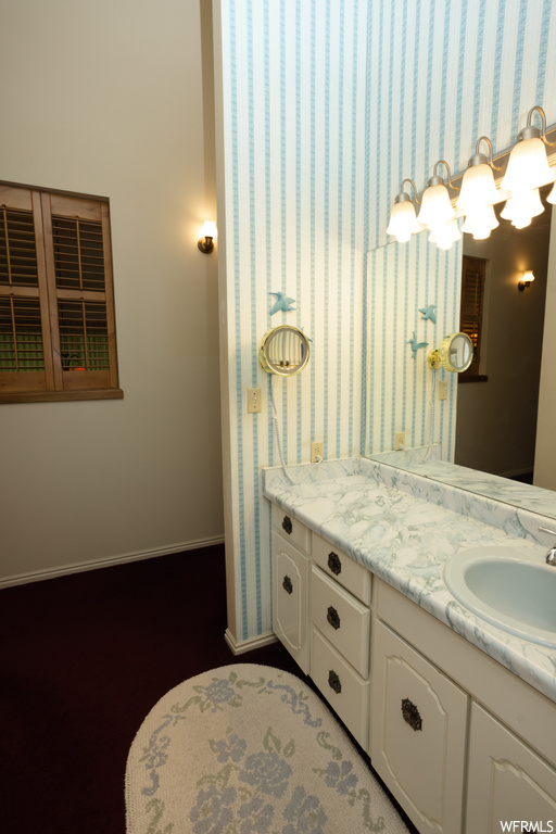Bathroom featuring mirror and vanity with extensive cabinet space
