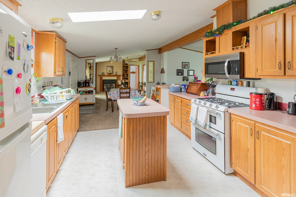 Kitchen featuring microwave, dishwasher, refrigerator, gas range oven, light flooring, light countertops, and brown cabinets