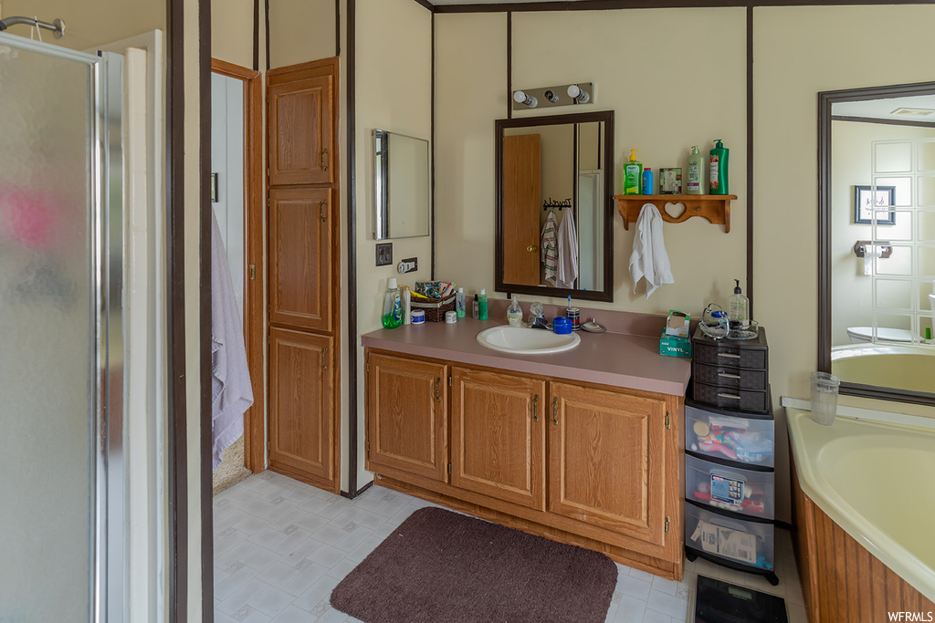 Bathroom with tile floors, mirror, vanity, and independent shower and bath