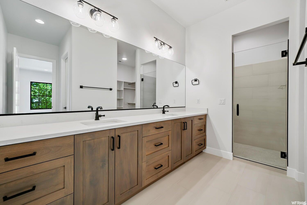 Bathroom featuring tile floors, natural light, shower with glass door, mirror, and dual bowl vanity