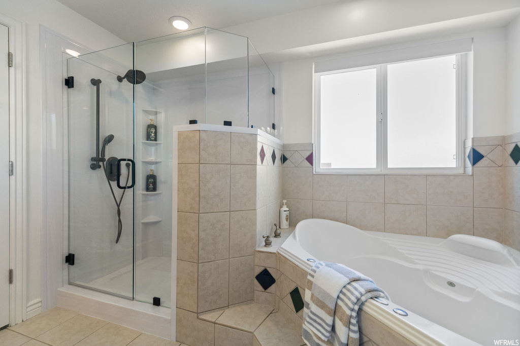 Bathroom with independent shower and bath, light tile flooring, and tile walls