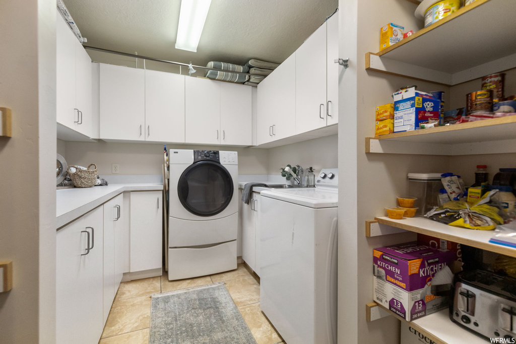 Laundry area featuring washing machine and clothes dryer and light tile floors