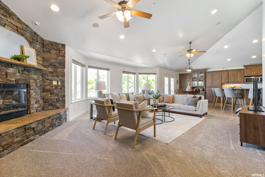 Carpeted living room with ceiling fan, lofted ceiling, and a fireplace