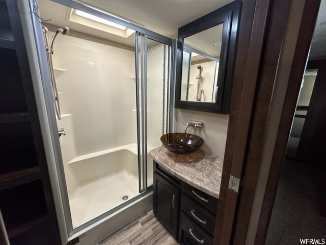 Bathroom with vanity with extensive cabinet space, mirror, and enclosed shower