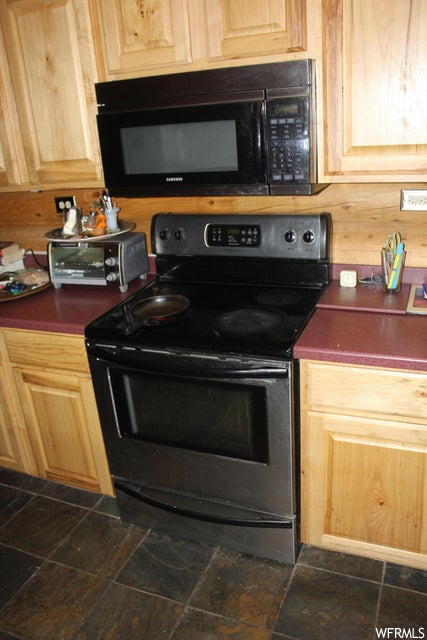 Kitchen with electric range oven, microwave, and dark tile floors