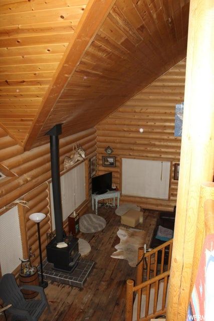 Unfinished attic with hardwood flooring, lofted ceiling, and TV