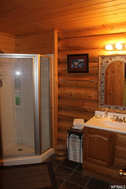 Bathroom featuring tile flooring, mirror, vanity, and enclosed shower