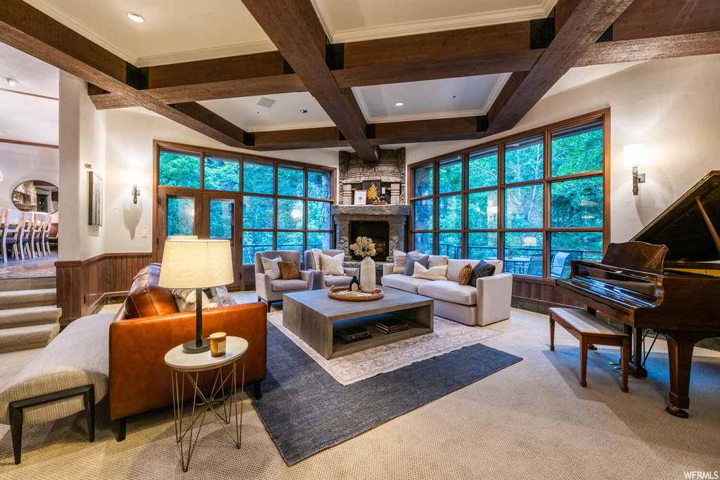 Carpeted living room with coffered ceiling, a fireplace, a healthy amount of sunlight, and beamed ceiling